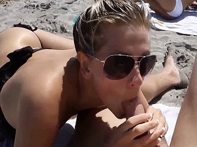 Une belle très blonde suce un mec sur une plage